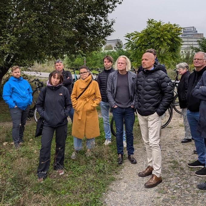 Mehrere Menschen stehen im Freien und hören anderen Menschen zu, die aber nicht zu sehen sind