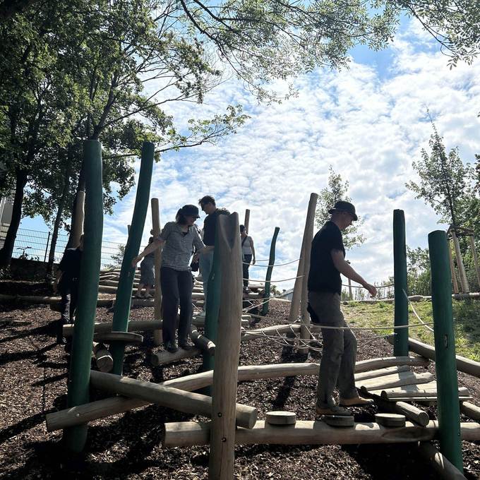 Erwachsene balancieren über eine Station des neuen Abenteuerspielplatzes in Kelsterbach